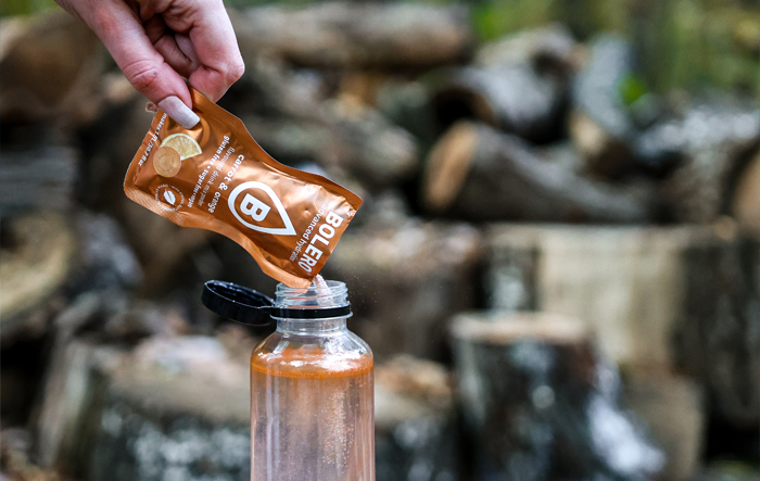 Wsypywanie saszetki Bolero do butelki z wodą podczas aktywności na świeżym powietrzu