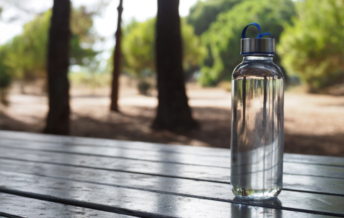 Szklana butelka z wodą stojąca na drewnianym stole na świeżym powietrzu