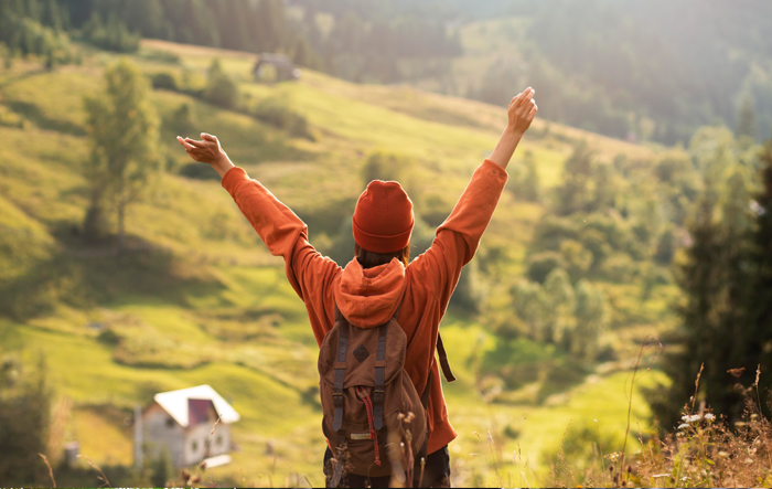 Osoba z plecakiem patrząca w dal podczas podr&oacute;ży w g&oacute;rskim krajobrazie