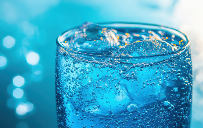 Szklanka wody gazowanej z widocznymi bąbelkami i kostkami lodu, symbol zdrowego i przyjemnego nawodnienia