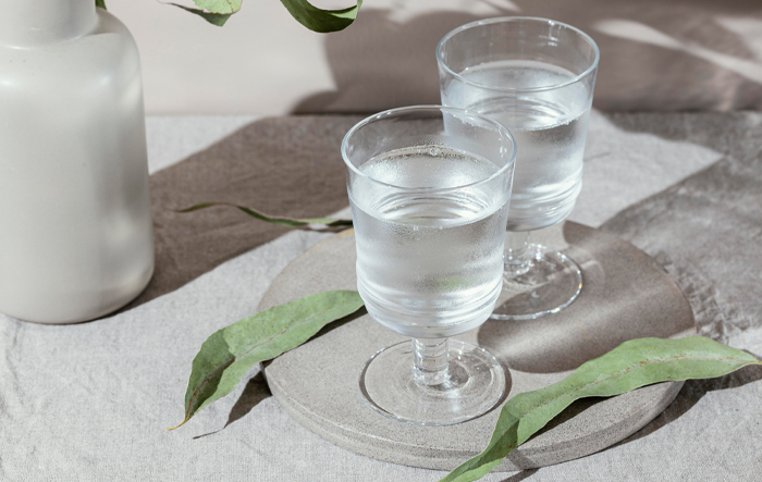 Dwa kieliszki wody na kamiennej podstawie, ilustracja tematu przewodnienia organizmu