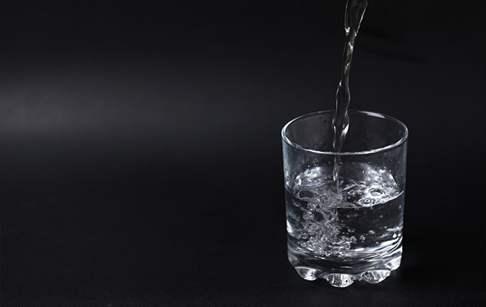 Szklanka wody na stoliku wieczorem – świadome nawodnienie organizmu przed snem