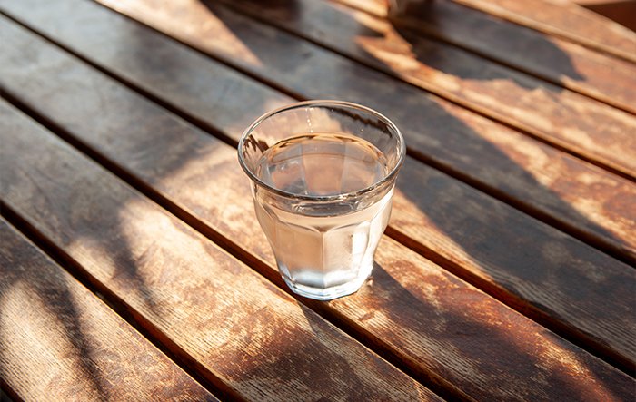 Szklanka wody stojąca na stole w naturalnym świetle jako element codziennego nawodnienia