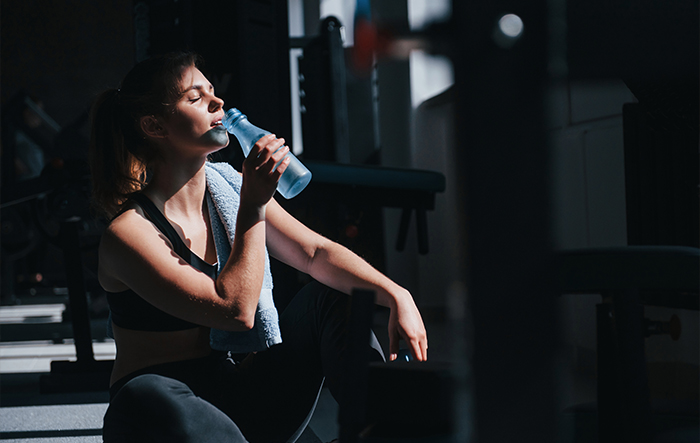 Kobieta pijąca wodę po wieczornym treningu – nawodnienie i elektrolity