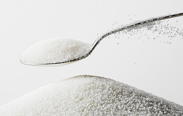 Łyżka z białym cukrem i kryształki cukru w zbliżeniu – ilustracja sacharozy