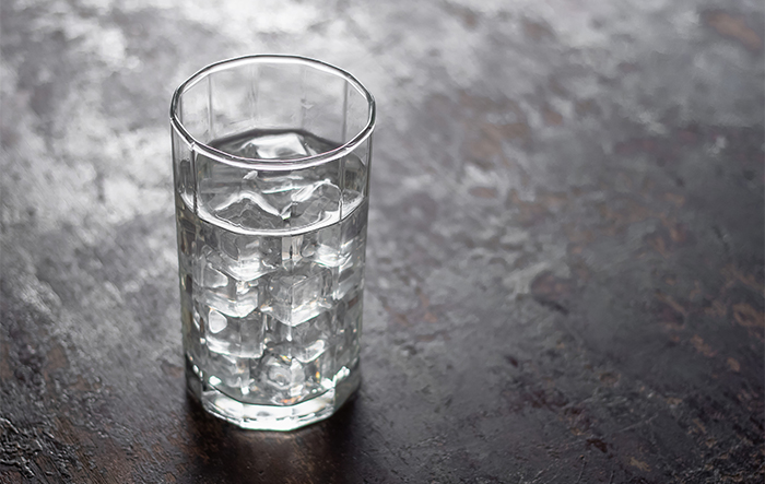 Szklanka wody z kostkami lodu na stole – symbol nawodnienia organizmu