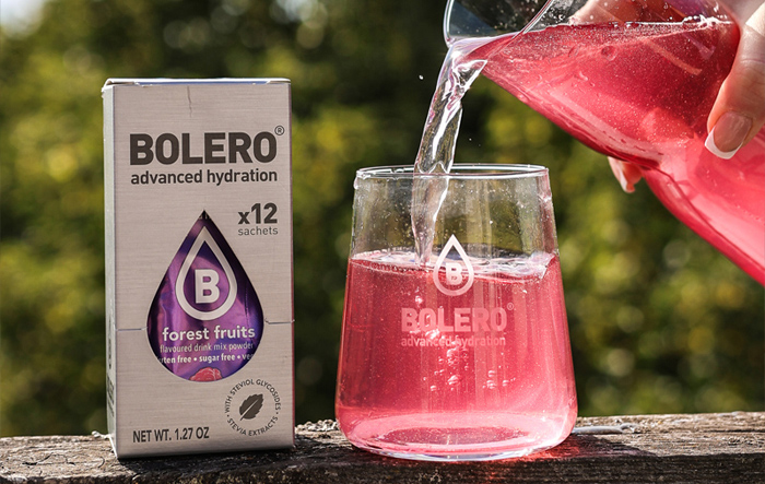 Saszetki napoju Bolero Forest Fruits i szklanka z różowym napojem – lekkie, bezcukrowe nawodnienie idealne dla seniorów
