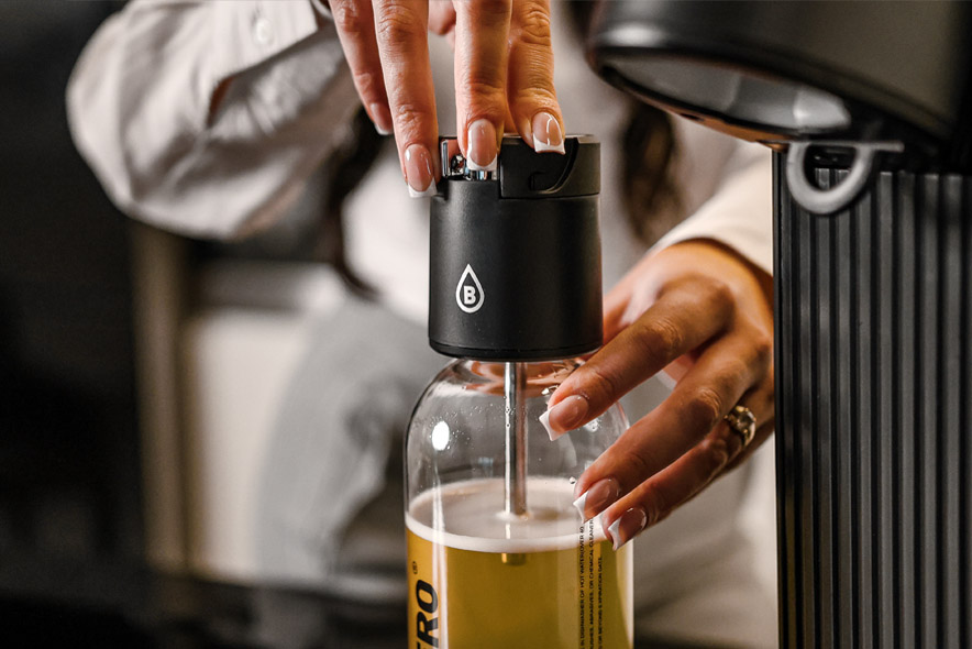 Zbliżenie na zakładanie głowicy Bolero Soda Maker na butelkę z napojem