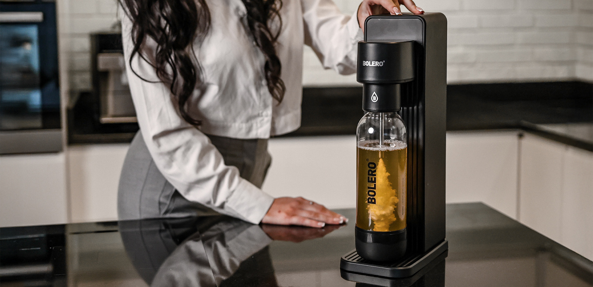 Saturator Bolero Soda Maker w kolorze czarnym podczas gazowania napoju w kuchni.
