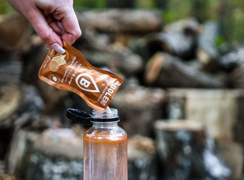 Przygotowanie napoju Bolero Carrot & Orange – wsypywanie saszetki o smaku marchewki i pomarańczy do butelki z wodą, napój bez cukru i glutenu.