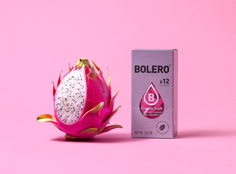 Bolero Dragon Fruit – opakowanie 12 saszetek obok świeżego smoczego owocu na różowym tle