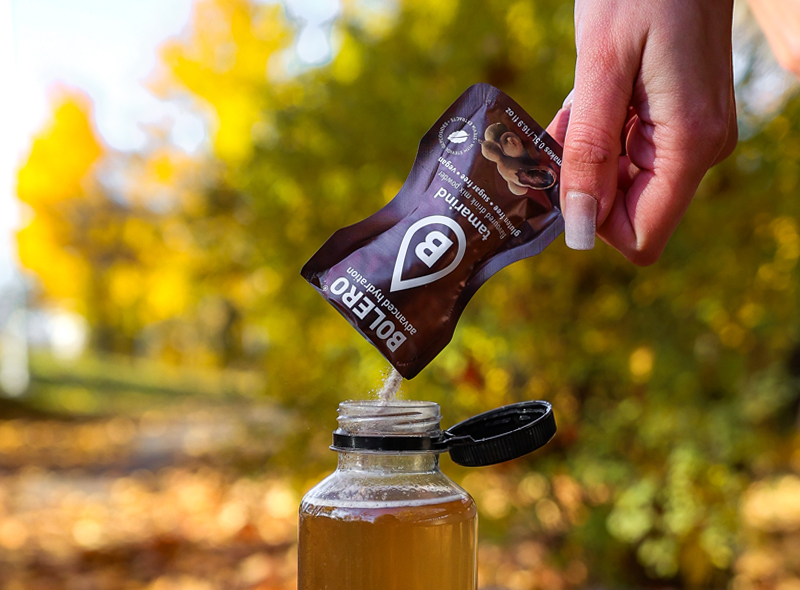 Przygotowanie napoju Bolero Tamarind – wsypywanie saszetki o smaku tamaryndowca do butelki z wodą, napój bez cukru i glutenu, idealny na jesienne dni.