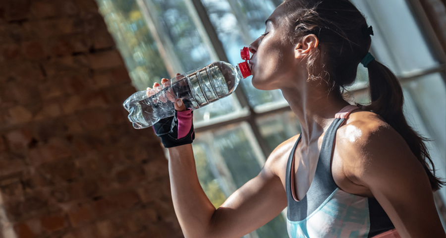 Kobieta pijąca wodę po treningu na siłowni – nawodnienie po wysiłku