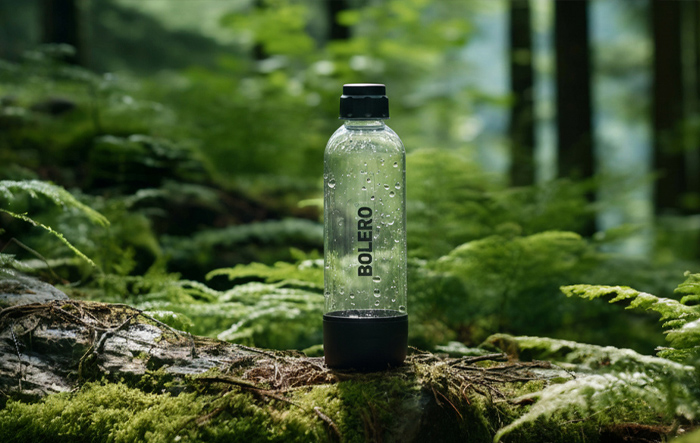 Butelka Bolero stojąca na pniu drzewa w lesie, symbol naturalnego nawodnienia