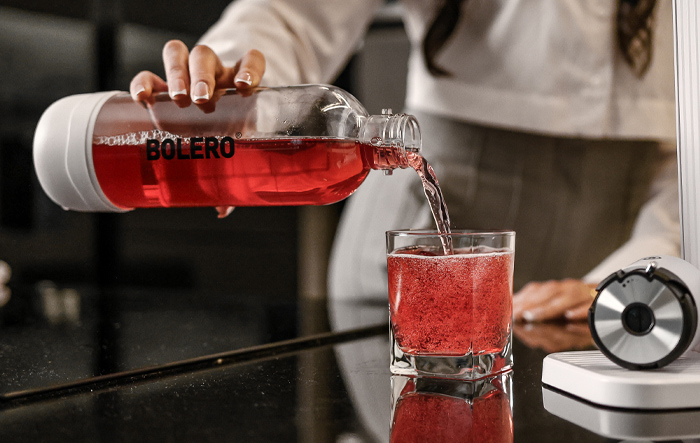 Nalewanie napoju Bolero z butelki do szklanki na blacie kuchennym