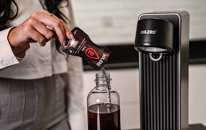 Wsypywanie saszetki Bolero do butelki z wodą przy użyciu saturatora Bolero