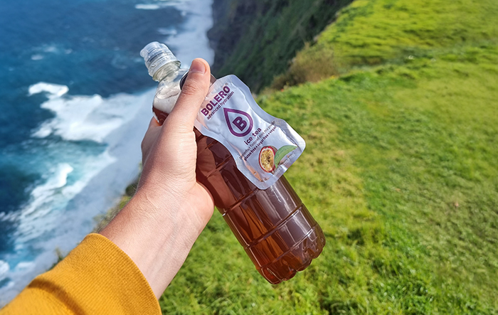 Butelka z mrożoną herbatą Bolero Ice Tea trzymana w ręce w plenerze nad klifem