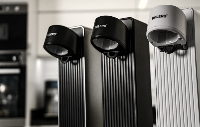 Zbliżenie szklanki wody w rękach kobiety w kuchni, obok świeżych owoc&oacute;w