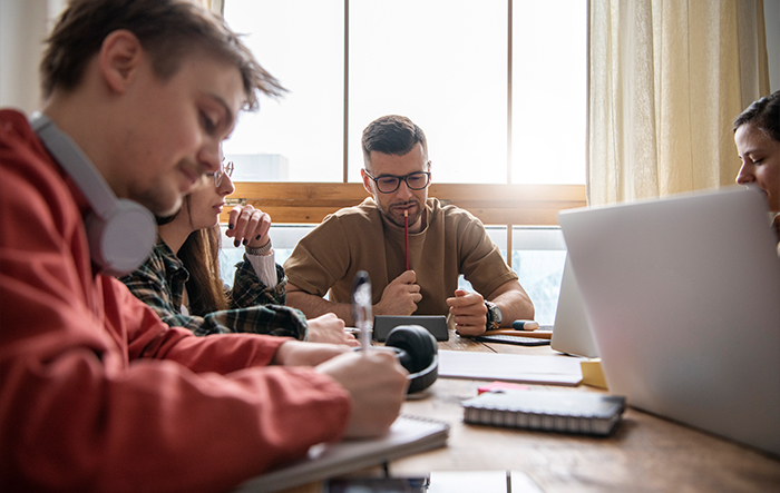Grupa osób uczących się i pracujących w skupieniu przy stole